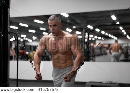 Muscular Athletic Bodybuilder Standing Training Chest And Shoulders Muscles On Fitness Equipment Wir