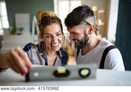 Mid Adults Couple With Leveler Indoors At Home, Relocation And Diy Concept.