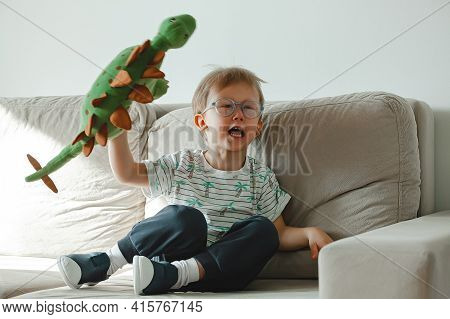A Child With Autism In Glasses Sits On The Sofa And Sad, Angry A