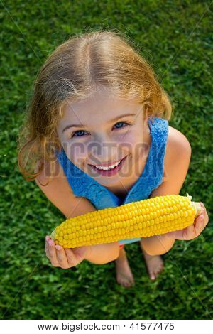 Child in the garden - lovely girl eating corn on the cob (GMO free)
