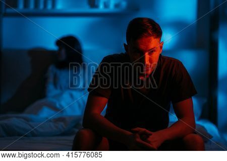 Couple Conflict. Domestic Abuse. Bad Relationship. Aggressive Man Sitting On Bed With Afraid Insecur