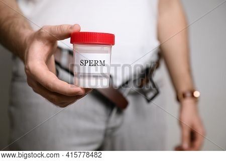 Donor With Unzipped Pants Holding Container Of Sperm, Closeup