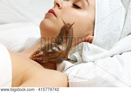 Beautiful Young Woman With A Snail On Her Face Lying On A White Bed, Cosmetic Procedure.