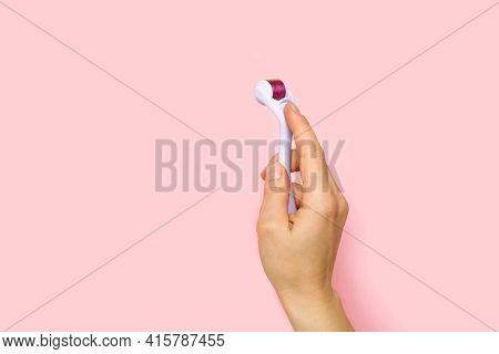 Dermaroller, Mesoroller, Microneedling. Cosmetic Tool With Micro Needles In Female Hand On Pink Back