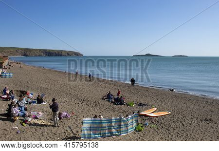 Aberdaron - Wales - April 3 2021 : Traditional Seaside Scene. Holiday Makers Relax On A Fine Sandy B
