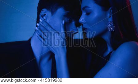 Seductive Woman Embracing Man In Blazer On Blue.