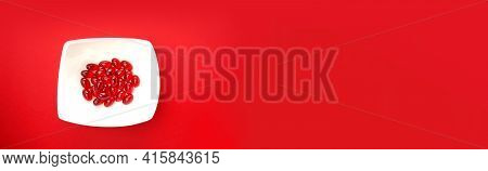 Krill Oil Capsules.banner. Red Gelatin Capsules With Krill Oil In A White Ceramic Cup On A Red Backg