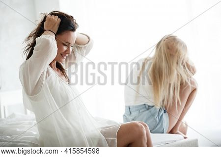 Family conflict and relations concept. Mother and daughter having quarrel and aguring at home. Sad woman and teenage girl sitting on bed. Not looking at each other.