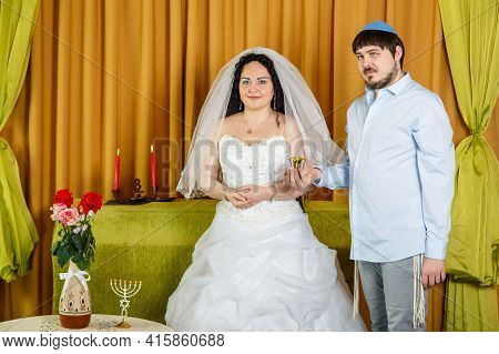 During The Chuppah Ceremony In The Synagogue, The Groom Holds A Glass Of Wine In His Hand, The Bride