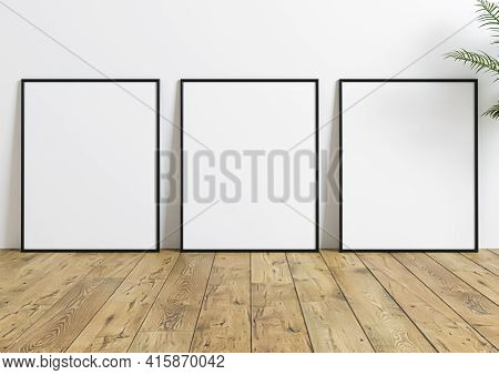 Triple 8x10 Vertical Black Frame Mockup On Wooden Floor And White Wall. Three Empty Poster Frame Moc