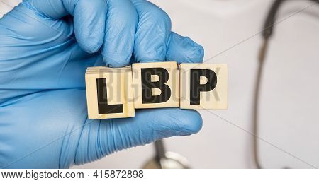 Lbp Low Back Pain - Word From Wooden Blocks With Letters Holding By A Doctor's Hands In Medical Prot