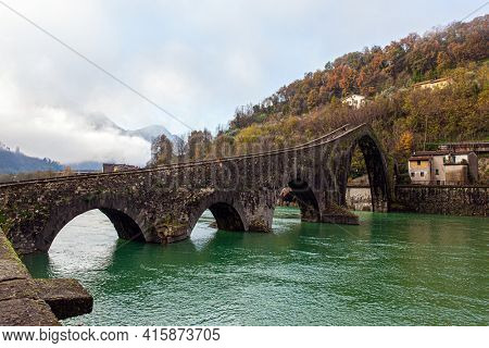  Ponte della Maddalena Bridge. Bridge built a thousand years ago. The vicinity of the city of Lucca. Cold windy winter day. Cold green waters of the Sercchio River. Italy. Province of Tuscany. 