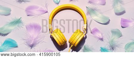 Banner With Yellow Headphones And Soft Feathers. Asmr Stress-relieving Sounds Concept, Flat Lay, Tre
