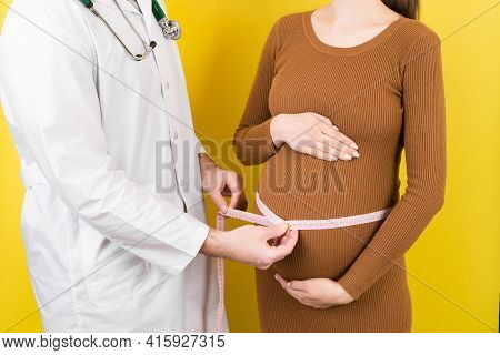 Happy Beautiful Pregnant Young Woman Touching Her Bare Tummy While A Doctor Is Measuring It