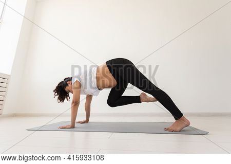 Young Flexible Pregnant Woman Doing Gymnastics On Rug On The Floor On White Background. The Concept 