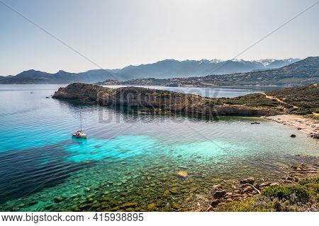 A Sailing Yacht Is Moored In A Bay On The Translucent Mediterranean Sea On The Coast Of La Revellata