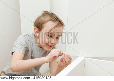 Boy Assembles A Bookshelf Hisself. Son Helping His Dad To Assembling New Furniture At Home. Furnitur