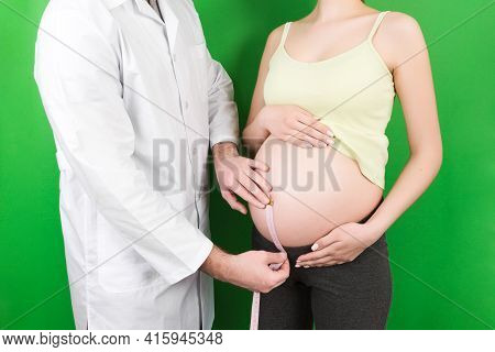 Happy Beautiful Pregnant Young Woman Touching Her Bare Tummy While A Doctor Is Measuring It