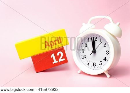 April 12nd. Day 12 Of Month, Calendar Date. White Alarm Clock On Pastel Pink Background. Spring Mont