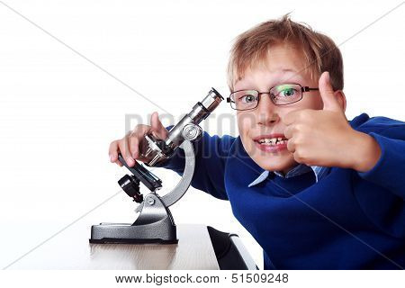 Beuatiful young boy in a blue jumper working with a microscope showing thumbs up