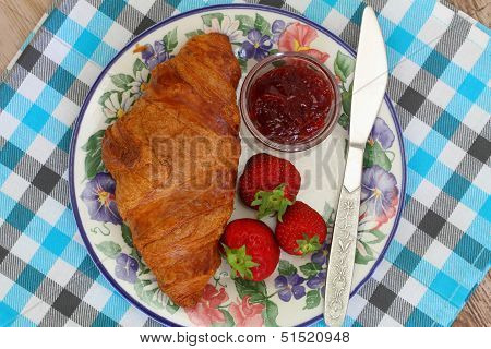 Croissant with strawberry jam and fresh strawberries