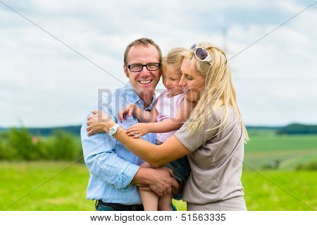 Happy Family with little girl or daughter in a meadow in summer