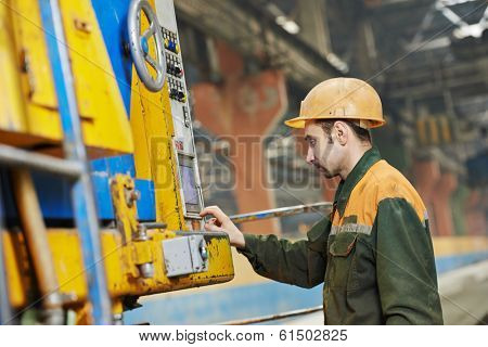 industrial worker operating concretemachine at factory workshop