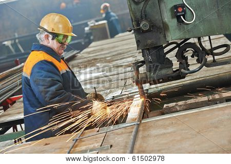 adult industrial worker at spot welding machine in factory workshop