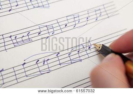 Hand with pen and music sheet