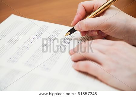 Hand with pen and music sheet