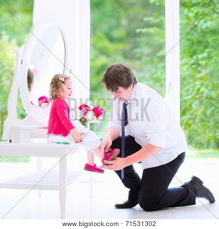 Father Helping His Daughter To Put On A Shoe