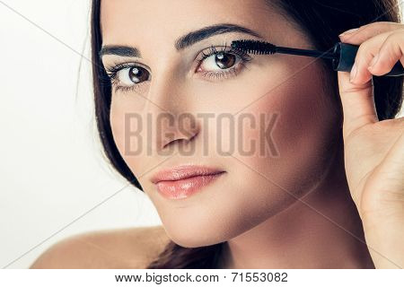 Woman applying mascara on her long eyelashes