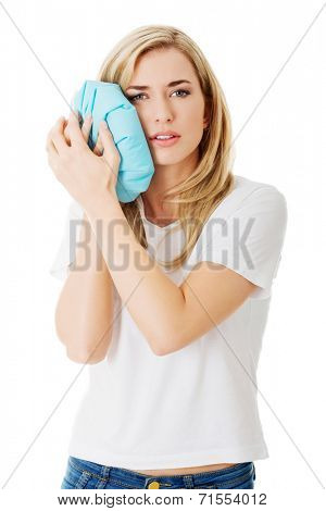 Woman heaving tooth ache, holding ice bag