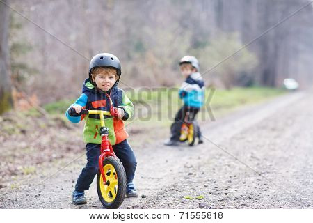 Two Active Little Sibling Boys Having Fun On Bikes In Forest