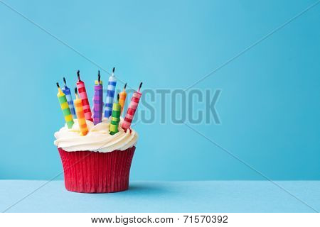 Birthday cupcake with blown out candles against a blue background