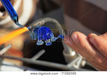 TEL AVIV, ISRAEL - FEBRUARY 11, 2012: Delicate work of the glass blower. The Artist-glass blower produces a graceful tiny figure of an elephant from color glass