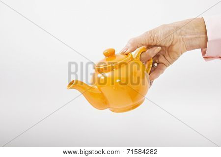 Senior businesswoman's hand holding teakettle over white background