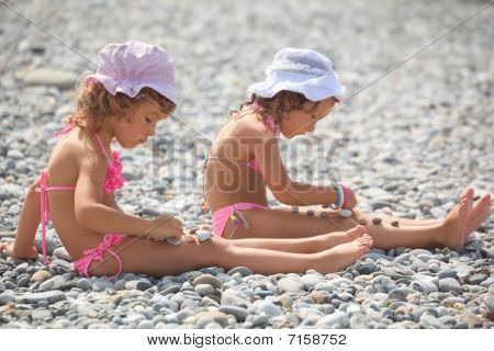 duas menininhas é brincar com pedras de seixo.