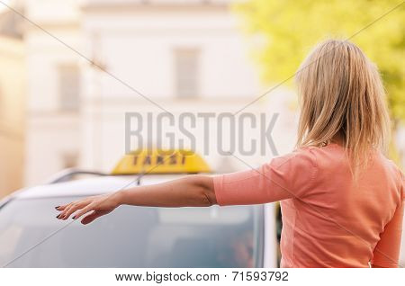 woman raising her arm to call a taxi