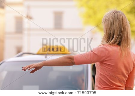 woman raising her arm to call a taxi