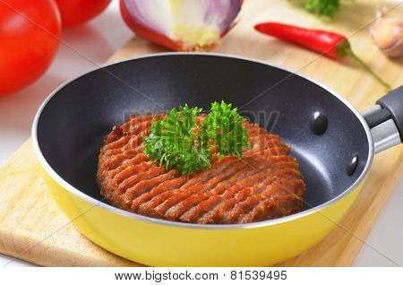 detail of fresh raw burger in the small teflon pan
