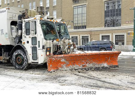 Truck with snowplow clearing street after snowstorm