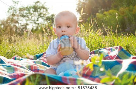 9 months old baby sitting on plaid and drinking juice