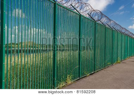 Razor Wire On Top Of Green Fence Guarding French Ferry Terminal.