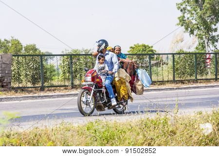 Mother, Father And Small Child Riding On Scooter Through Busy Highway
