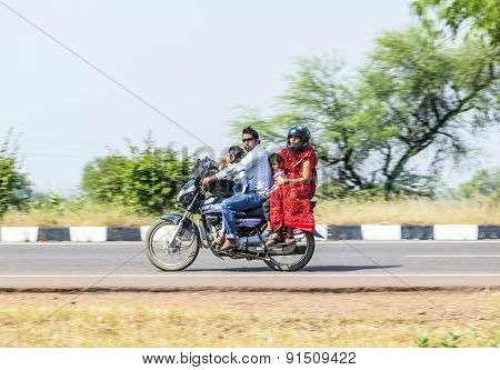 Mother, Father And Small Child Riding On Scooter Through Busy Highway