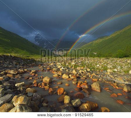 Summer landscape with a rainbow in the mountains above the river. Zemo Svaneti, Georgia