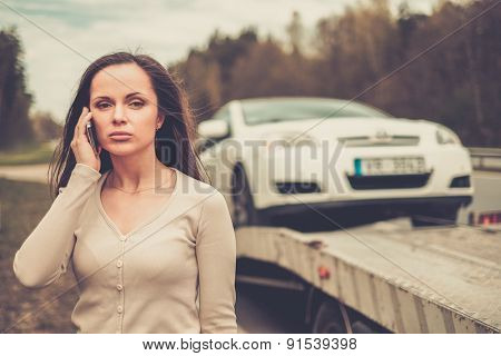 Woman calling while tow truck picking up her car