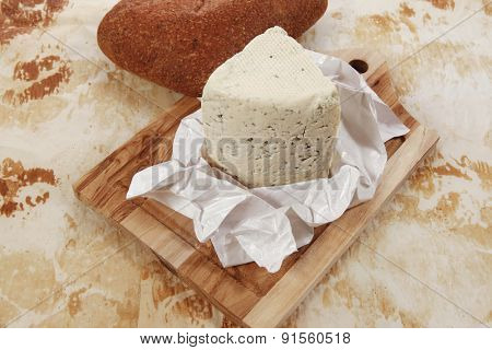 aged italian deli fresh blue stilton cheese and rye ciabatta served on wooden cutting plate on used baking paper as background