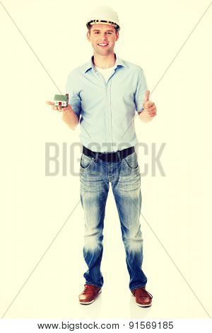 A forewoman holding a model house in hand and gesturing OK